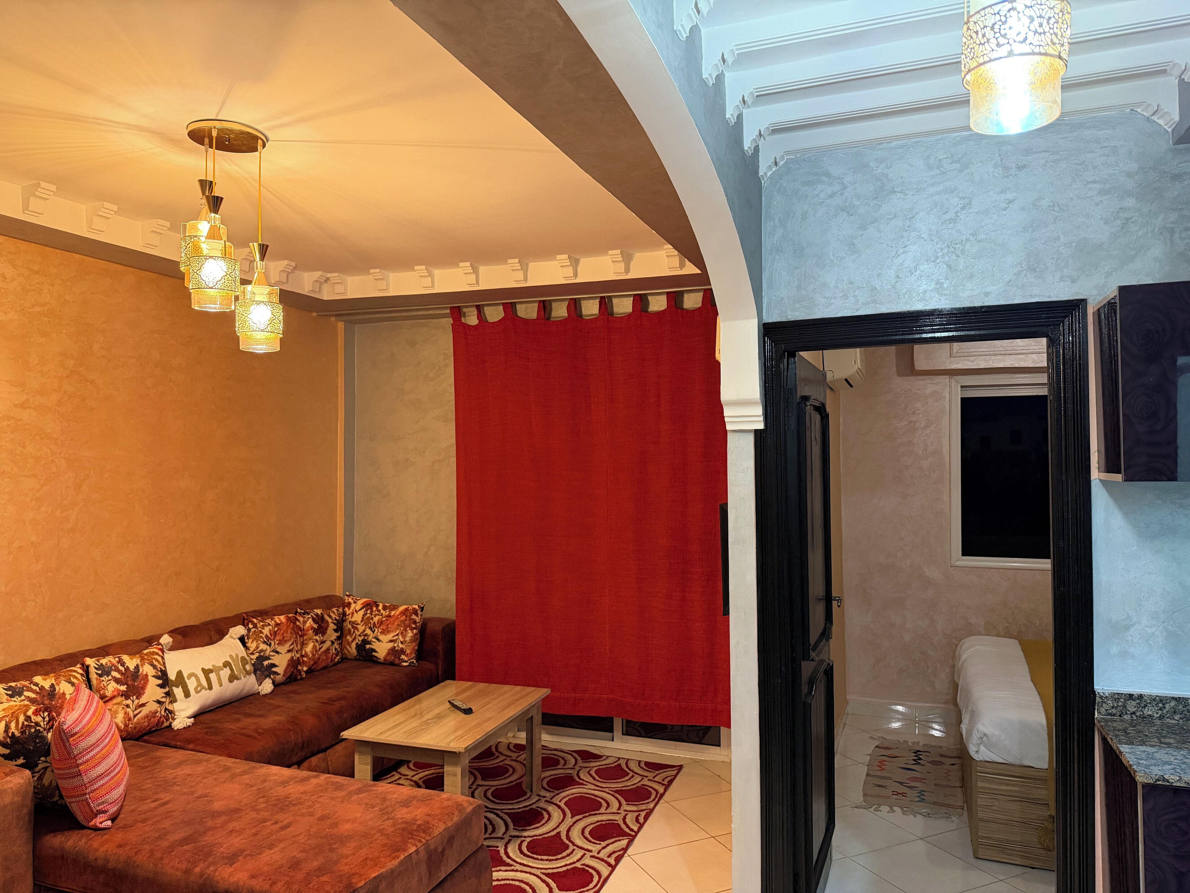 A living room with a brown sofa, a red curtain, and a wooden coffee table.