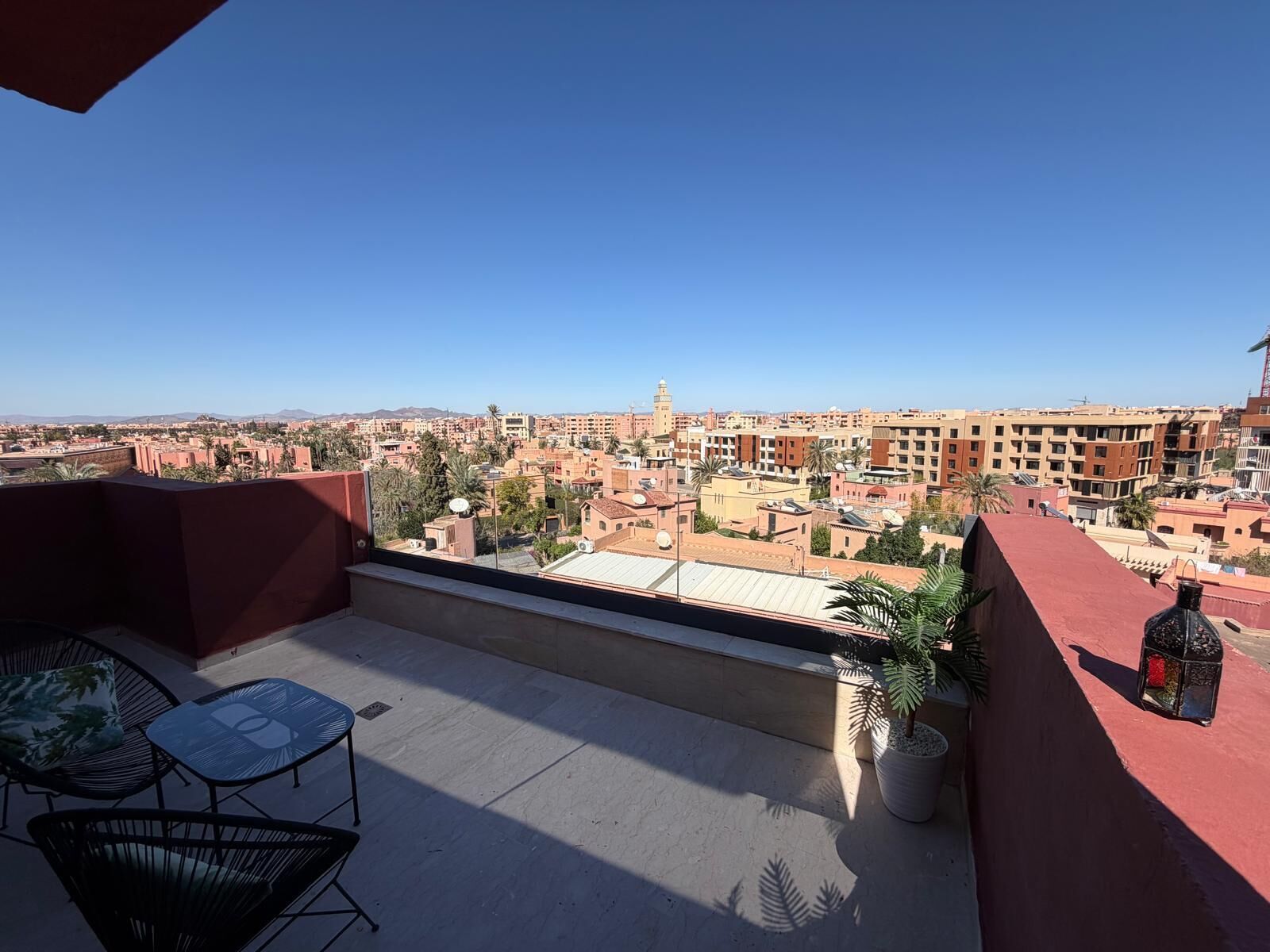 A balcony with a clear view of a cityscape, including buildings and a distant mountain range.