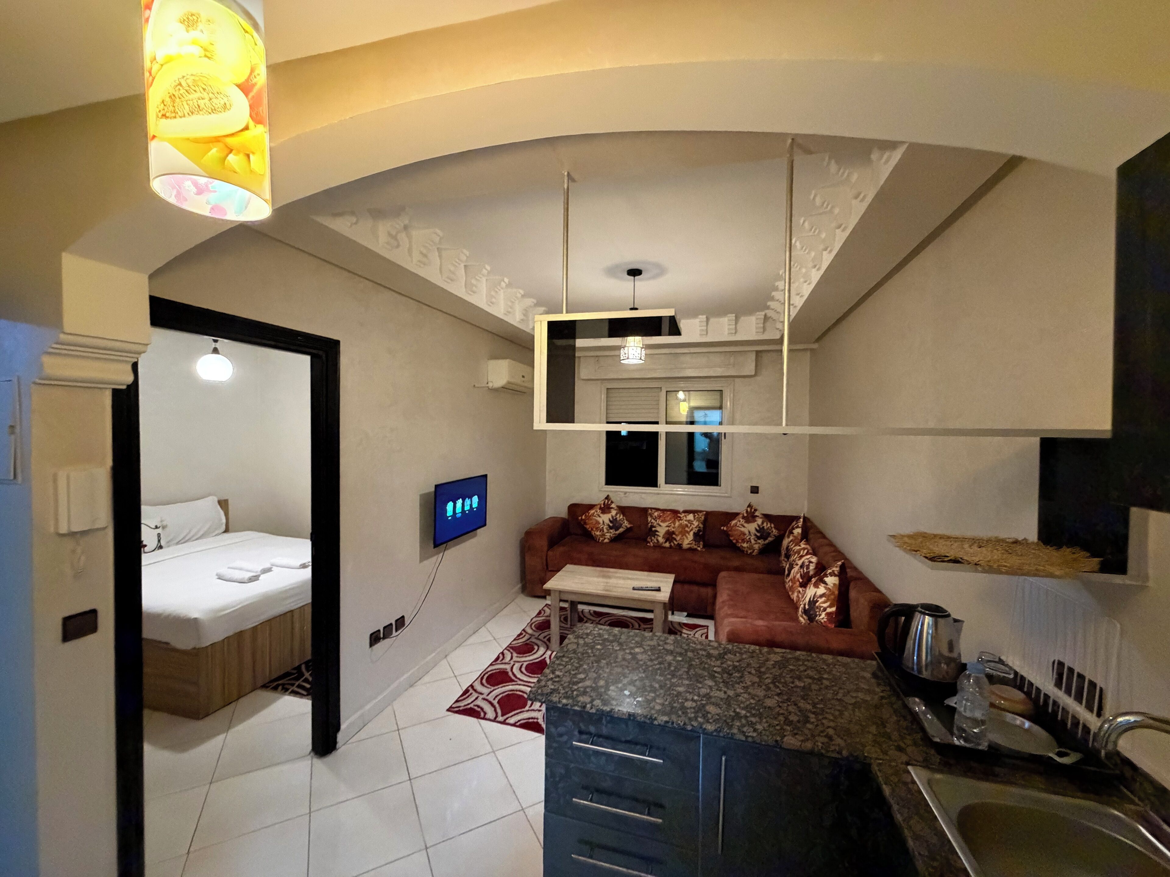 Un ambiente compatto con angolo cottura, divano, zona pranzo e camera da letto separata.