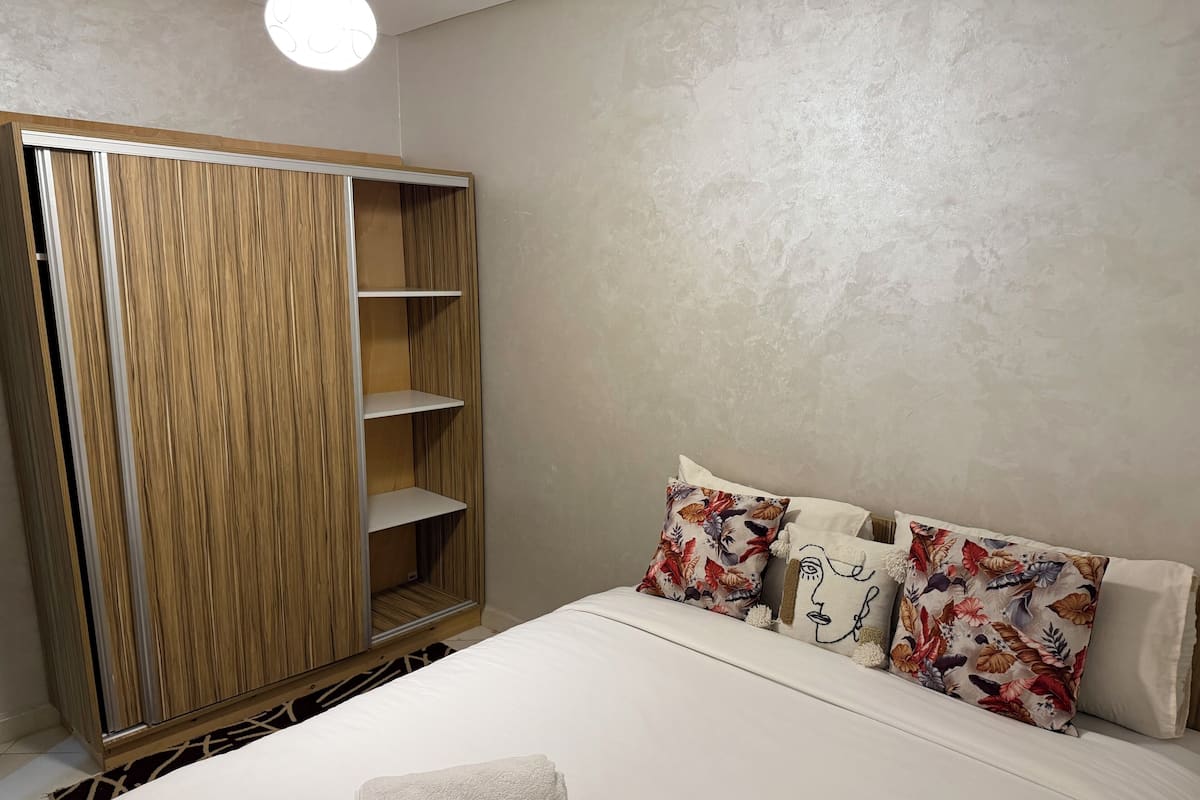 A bedroom with a bed, a wardrobe, and a nightstand.