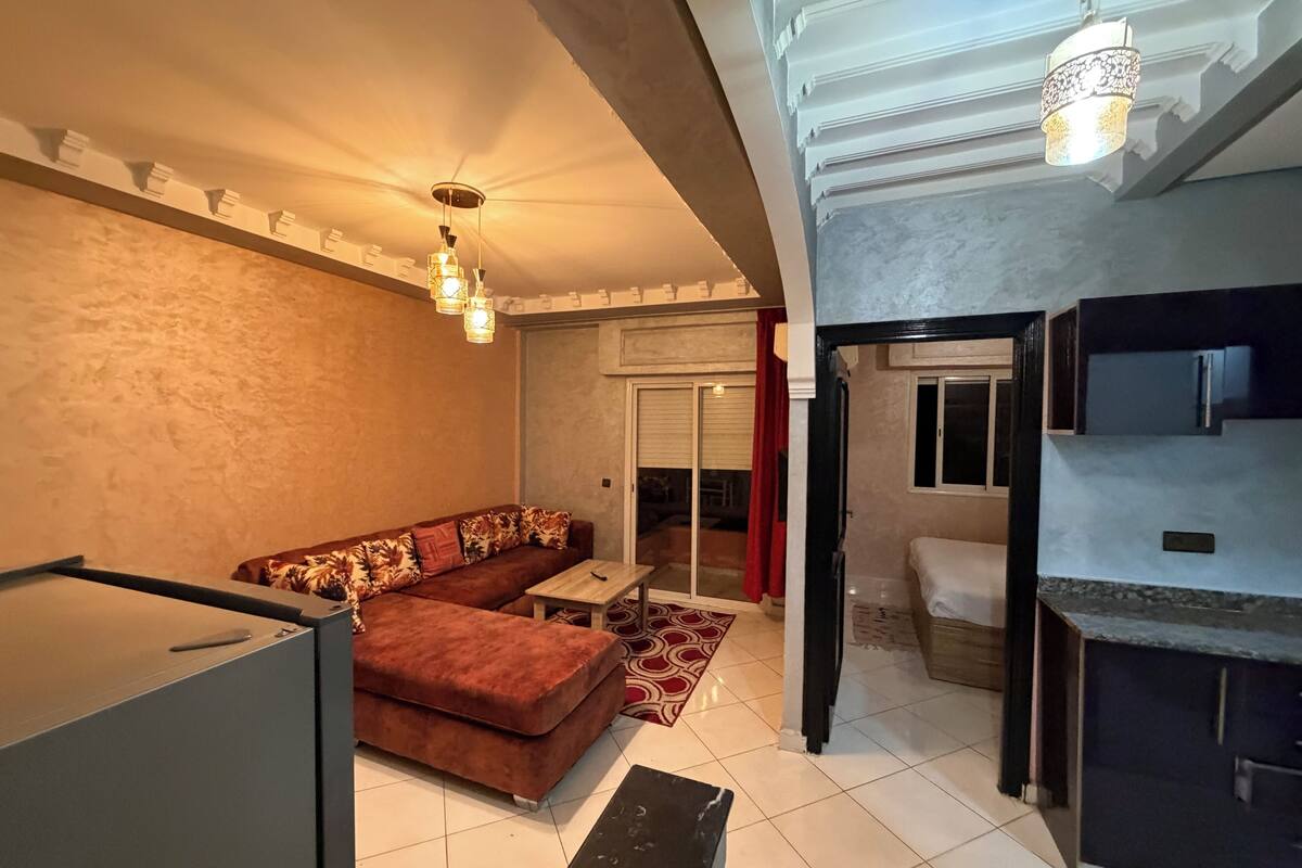 A modern living room with a sofa, a coffee table, and a patterned rug. There is a staircase leading to another level.