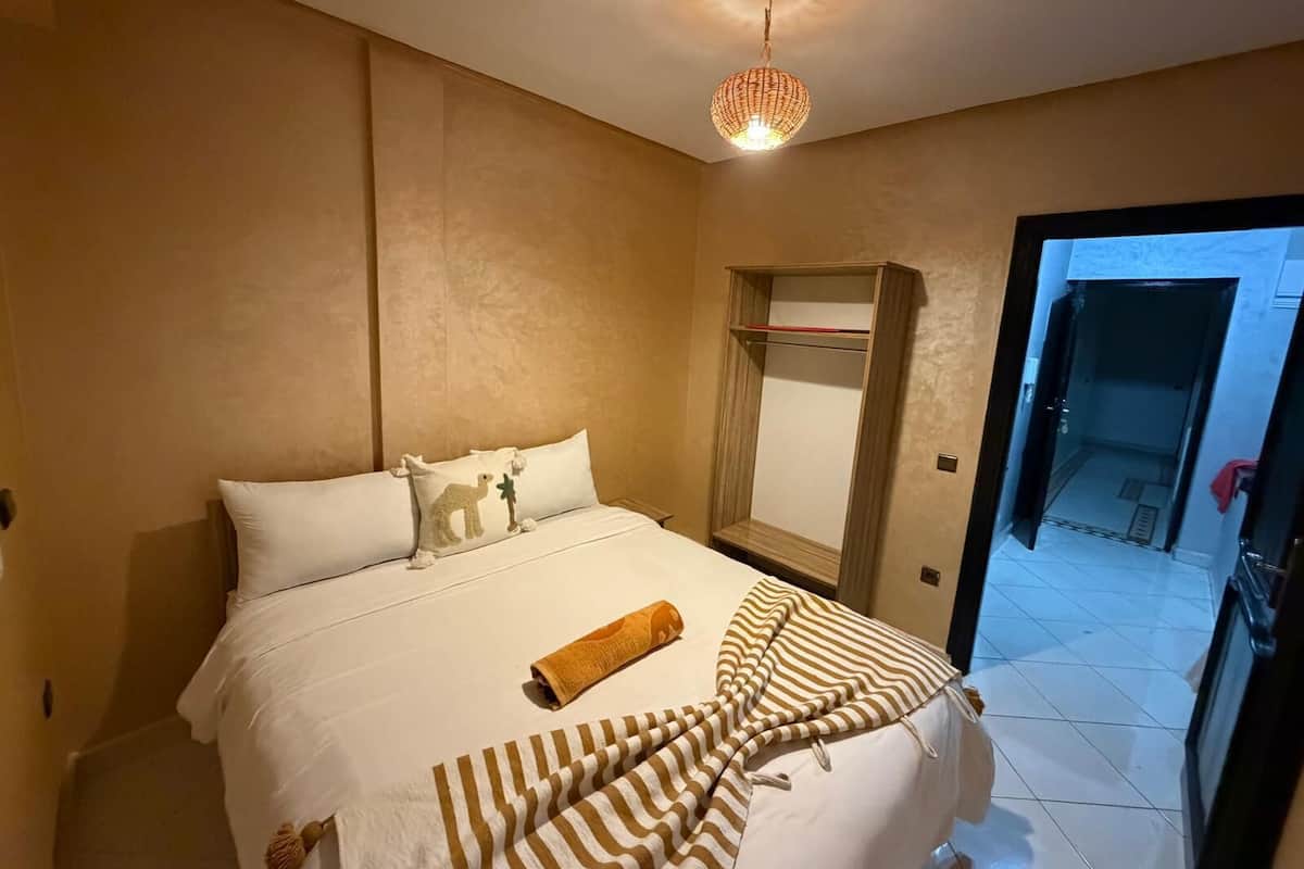 A hotel room with a bed, a wardrobe, and a hanging light fixture.