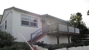 A two-story house with a covered porch, a staircase, and a small garden area. - Cozy 1-bedroom sunset beach apartment in San Diego (San Diego)