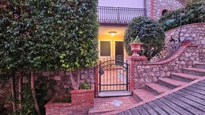 A stone staircase leading to a yellow building with a metal gate, surrounded by greenery and a stone wall. - Taormina Home La Terrazza di Fede. 5 minutes walk from downtown. Private car park (Taormina)