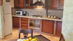 A compact kitchen with a refrigerator, microwave, stove, oven, and wooden cabinets. - Taormina Home La Terrazza di Fede. 5 minutes walk from downtown. Private car park (Taormina)