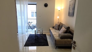 A modern living room with a sofa, a coffee table, and a floor lamp. There is a balcony visible through the window. - Apartments Ana in the heart of Split (Split)