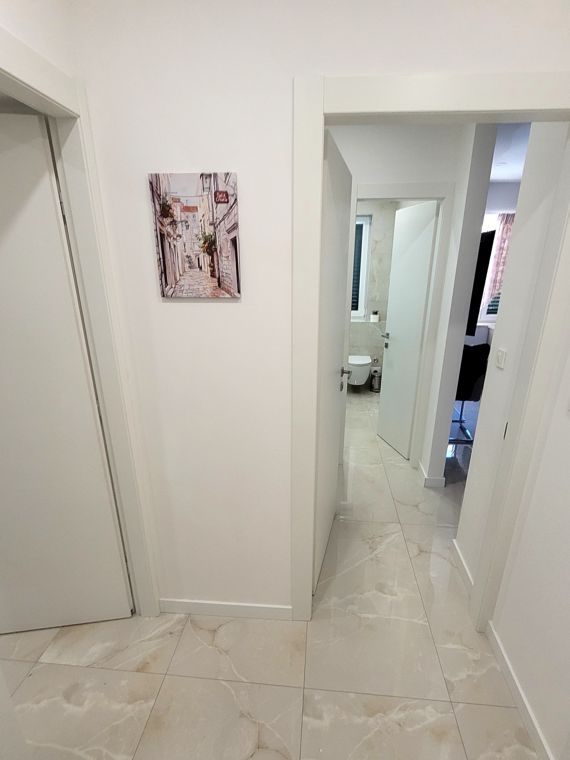 A hallway with a tiled floor leading to a bathroom.