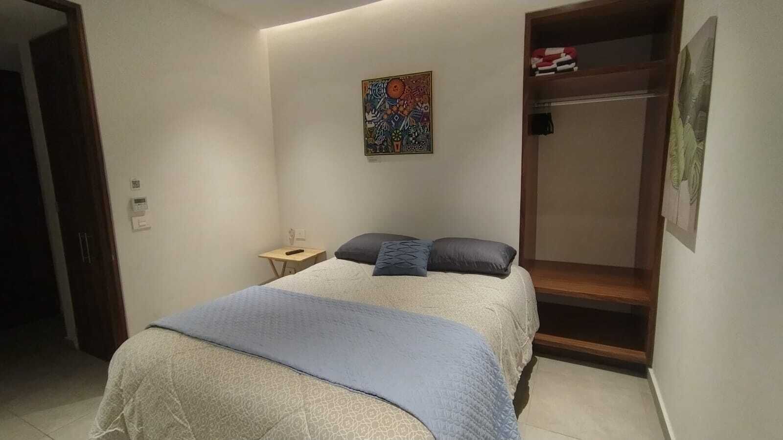 A bedroom with a bed, bedside table, and a small table with a lamp.