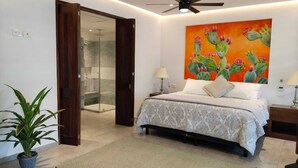 Ein Schlafzimmer mit Bett, Glasdusche, einem Kaktusgemälde und einer Topfpflanze.