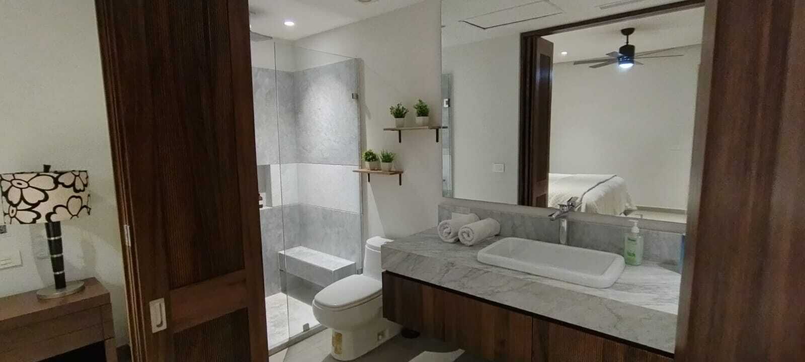 A modern bathroom with a shower, toilet, and vanity.