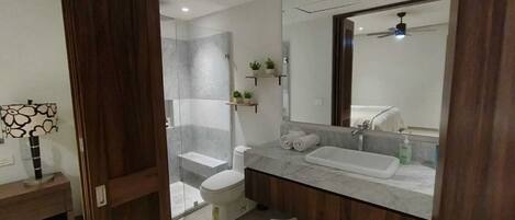 A modern bathroom with a shower, toilet, and vanity.