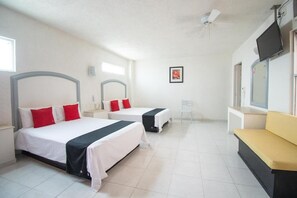A hotel room with two beds, a small desk, a chair, a sofa, and a television.