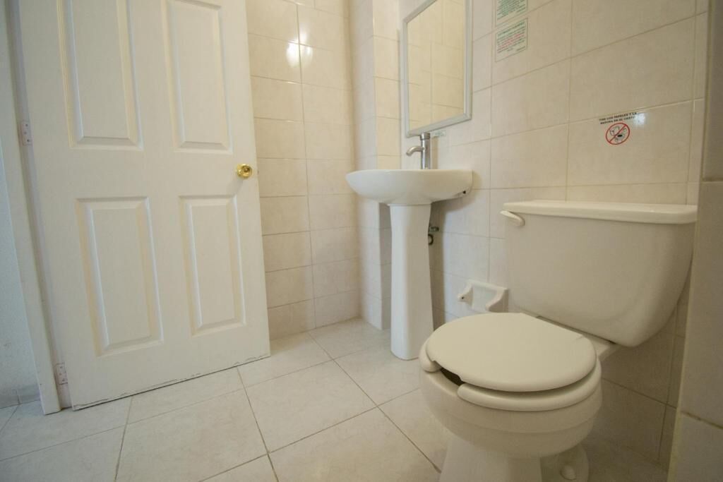 Un baño con inodoro blanco, lavabo y espejo.