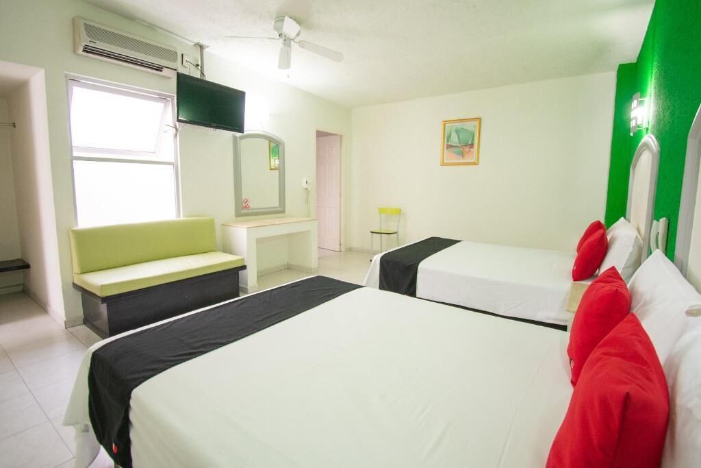 A hotel room with two beds, a desk, a chair, a mirror, and a television.