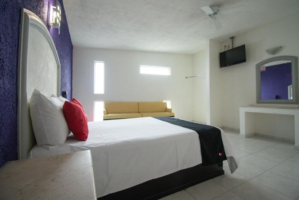 Quarto com uma cama, um sofá, uma televisão e uma janela.