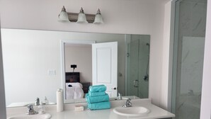 Un baño con dos lavamanos, un espejo grande y una ducha.