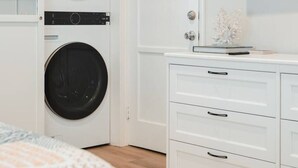 A bedroom with a bed, a white dresser, and a wall-mounted TV. - Spacious Suite: Minutes to Everything! (San Diego)