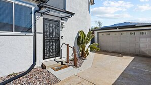 A residential house with a garage, a black front door, and a concrete driveway. - Spacious Suite: Minutes to Everything! (San Diego)