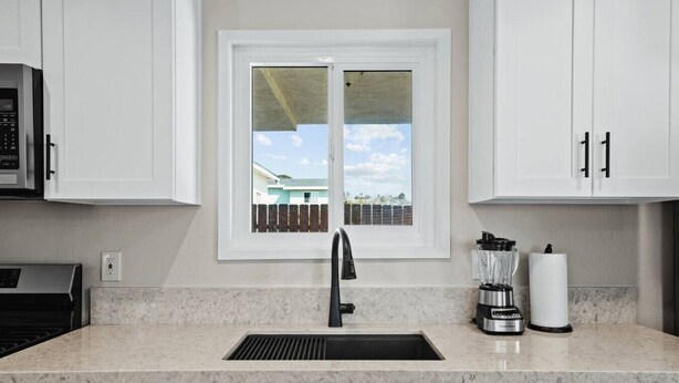 A kitchen with a window, a sink, a stove, and cabinets. - Spacious Suite: Minutes to Everything! (San Diego)