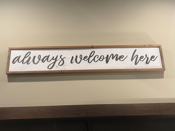Un letrero de bienvenida con el texto 'siempre bienvenidos aquí' en un marco de madera.