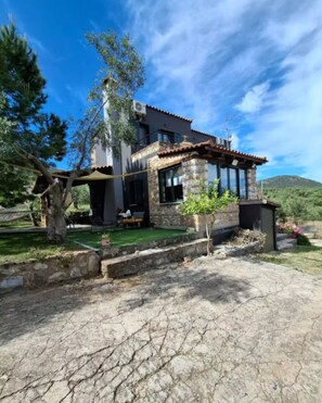 A modern house with a stone facade, large windows, and a green lawn.