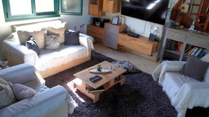 Ein Wohnzimmer mit einer Couch, einem Couchtisch, einem Fernseher und einem Bücherregal.