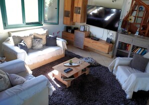 A living room with a sofa, a coffee table, a TV, and a bookshelf.