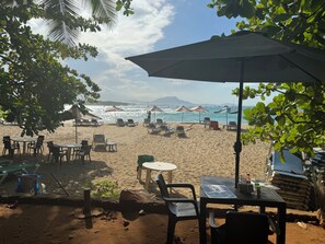 A beachside seating area with tables and chairs under umbrellas, overlooking the sea. - Well-located apartment 3 minutes from the beach 312 (Sosúa)
