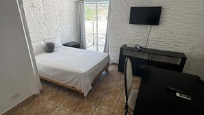 Ein kleiner, gut beleuchteter Raum mit einem Bett, einem Schreibtisch und einem Fernseher.