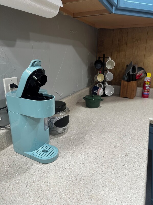 A kitchen with a teal coffee maker, a green pot, and a fire extinguisher.