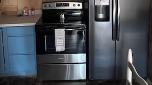 A modern kitchen with blue cabinets, a stainless steel microwave, oven, and refrigerator. - Walk to Lake • 🔥Fire Pit • Pets Welcome 🐾.             + golf ⛳️ (Canadian)