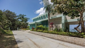A modern building with a concrete pathway and lush greenery. - Casa Sea Glass 5 bedroom home waterfront with Pool (Roatan)