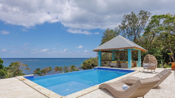 A pool area with a gazebo, lounge chairs, and a view of the sea. - Casa Sea Glass 5 bedroom home waterfront with Pool (Roatan)