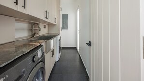 A laundry room with a washing machine, a sink, and cabinets. - Casa Sea Glass 5 bedroom home waterfront with Pool (Roatan)