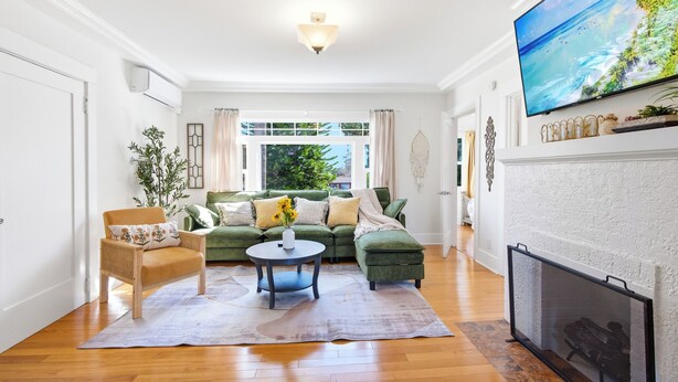 A living room with a green sofa, a round coffee table, and a fireplace. - King Bed Comfort Ultra Spacious Gem Prime Location south pasadena! (South Pasadena)