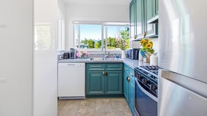 A modern kitchen with teal cabinets, a stainless steel refrigerator, and a dishwasher. - King Bed Comfort Ultra Spacious Gem Prime Location south pasadena! (South Pasadena)