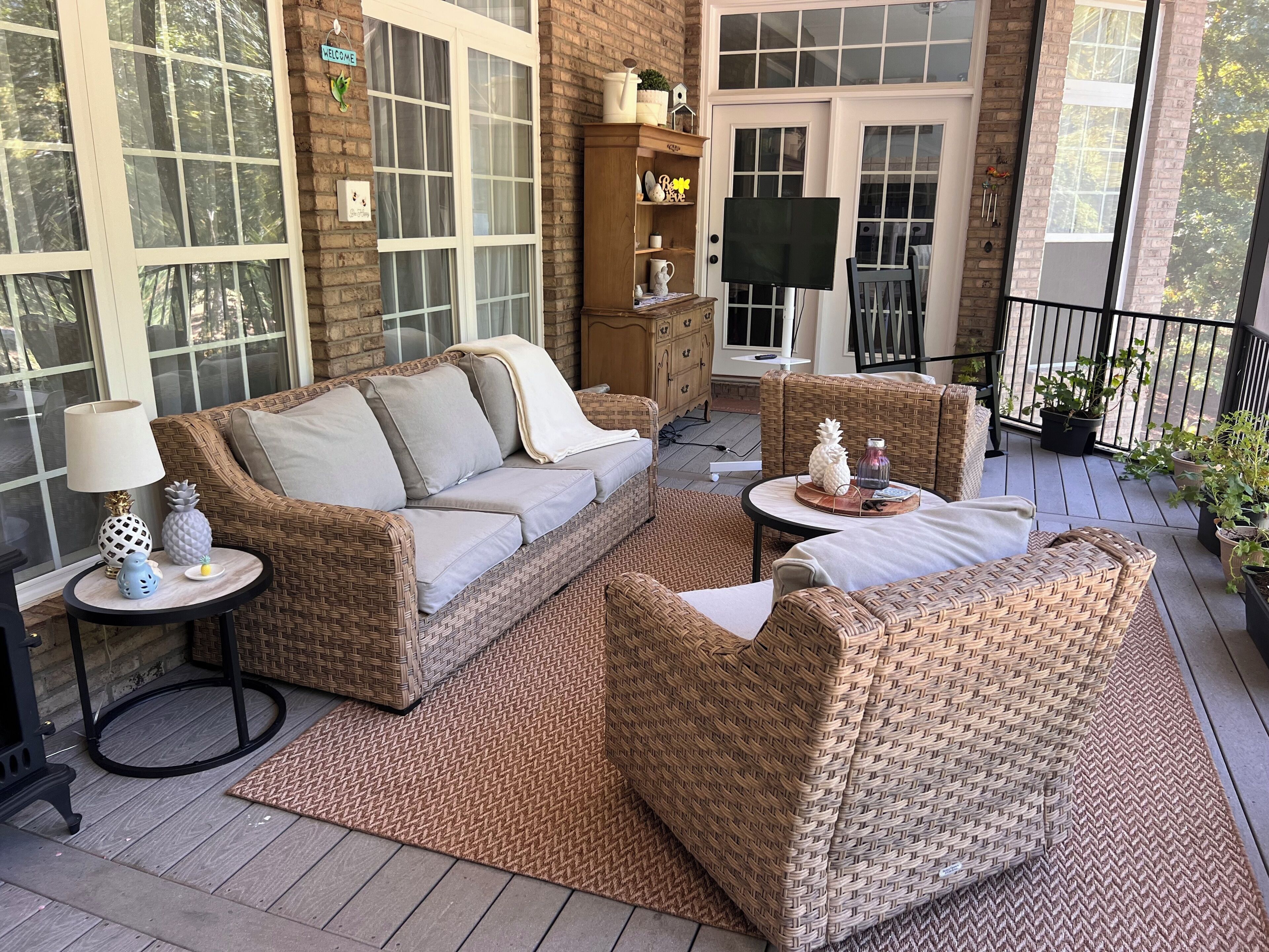 A cozy outdoor seating area with wicker furniture, a cushioned sofa, and a small table with decorative items.