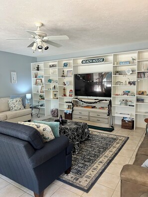 A living room with a sofa, a coffee table, a TV, and a bookshelf labeled 'BEACH HOUSE'. - Spacious 4-bedroom4bth house in private golf course community ready for Masters (North Augusta)