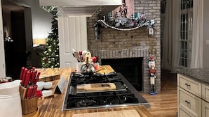 Una cocina moderna con una isla central, chimenea de ladrillo y adornos navideños.