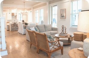 A spacious living area with a sofa, chairs, a dining table, and a kitchen in the background. - WaterColor-Golf cart-5 Bikes & Resort Amenities  (Santa Rosa Beach)
