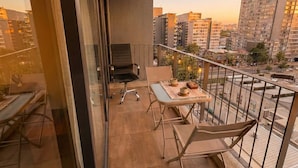 A balcony with a table, chairs, and a small grill. - Ñuñoa Metro Irarrazaval - Domus Travels (Santiago)