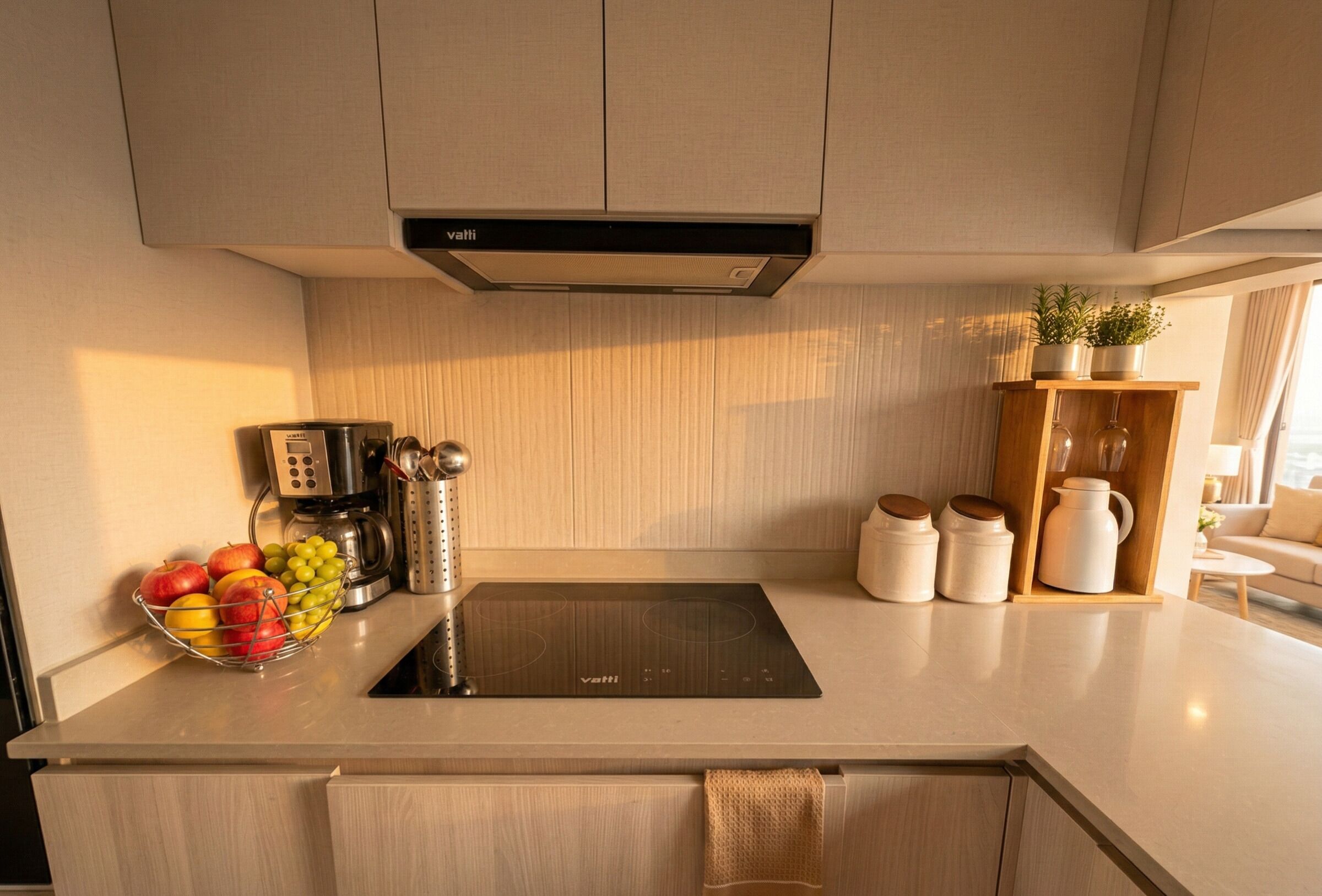 A modern kitchen with a built-in stove, a coffee maker, a fruit bowl, and a shelf with kitchenware.
