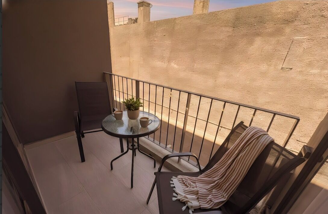 A balcony with a round table, two chairs, and a potted plant.