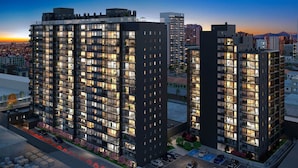 A high-rise residential building with multiple balconies, a parking area, and a sunset view. - Ñuñoa Metro Irarrazaval - Domus Travels (Santiago)