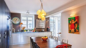 Une cuisine moderne avec une table à manger en bois, une horloge et un tableau accroché au mur.