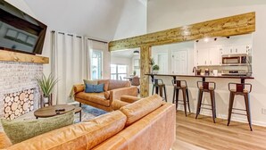 A spacious living area with a fireplace, leather sofas, and a kitchen area with bar stools. - NEW TO VRBO SPECIAL! 4 Bedroom Home- 6 mi to Airport, 11 mi to Downtown (Pooler)