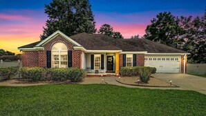 A two-story brick house with a garage, a front porch, and a well-maintained lawn. - NEW TO VRBO SPECIAL! 4 Bedroom Home- 6 mi to Airport, 11 mi to Downtown (Pooler)