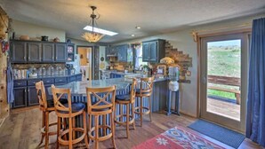 A spacious kitchen with a central island, bar stools, and a view to the outdoors. - Cozy Black Hills Home on 13 Acres w/ Deck & Views!! (Hot Springs)