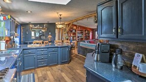 A cozy kitchen with dark cabinets, a central island, and a coffee machine. - Cozy Black Hills Home on 13 Acres w/ Deck & Views!! (Hot Springs)