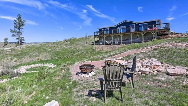 A two-story house with a deck and a fire pit in the front yard. - Cozy Black Hills Home on 13 Acres w/ Deck & Views!! (Hot Springs)